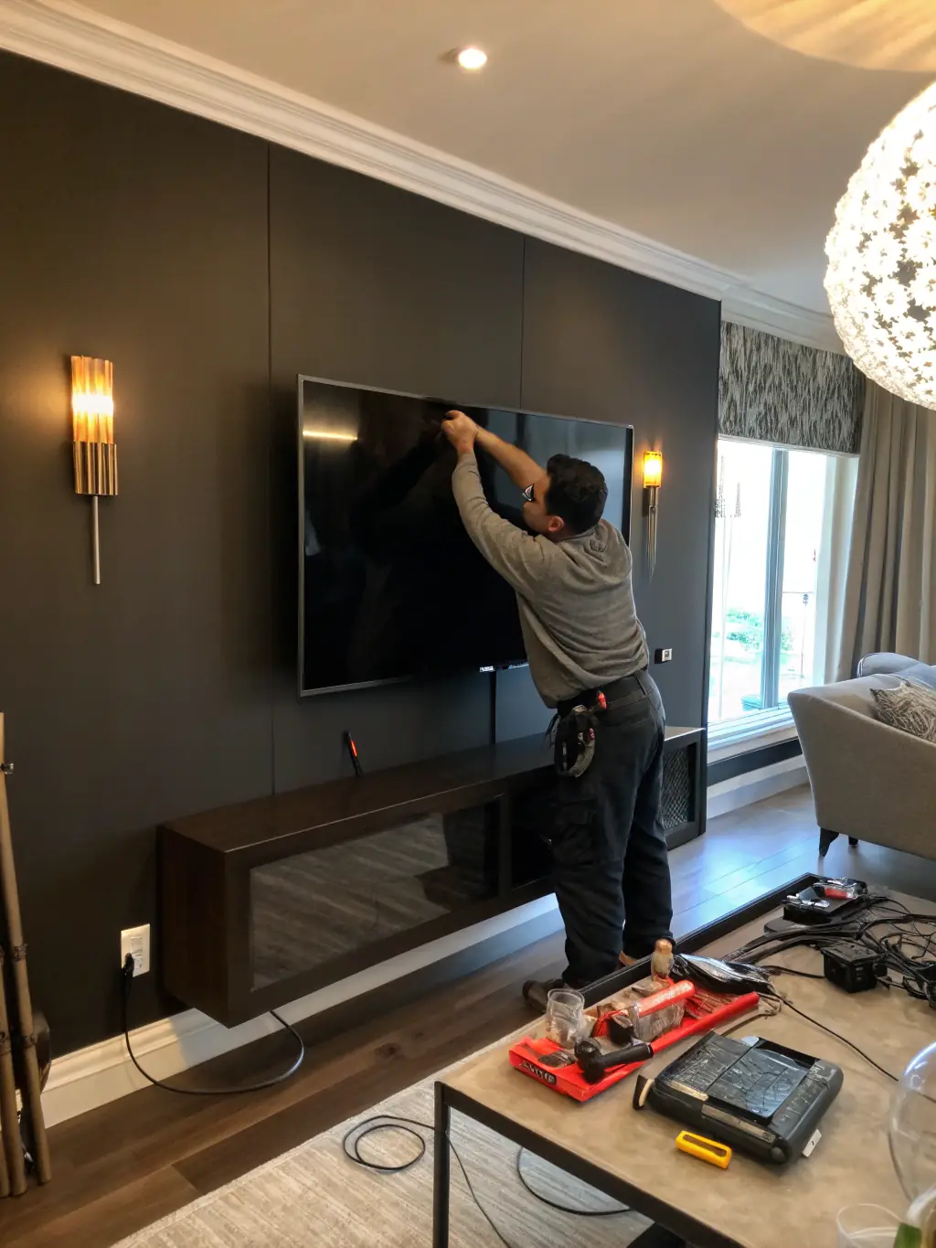 A close-up shot of a technician's hands expertly concealing wires behind a wall-mounted TV, showcasing the clean and professional finish that HangItUp provides.